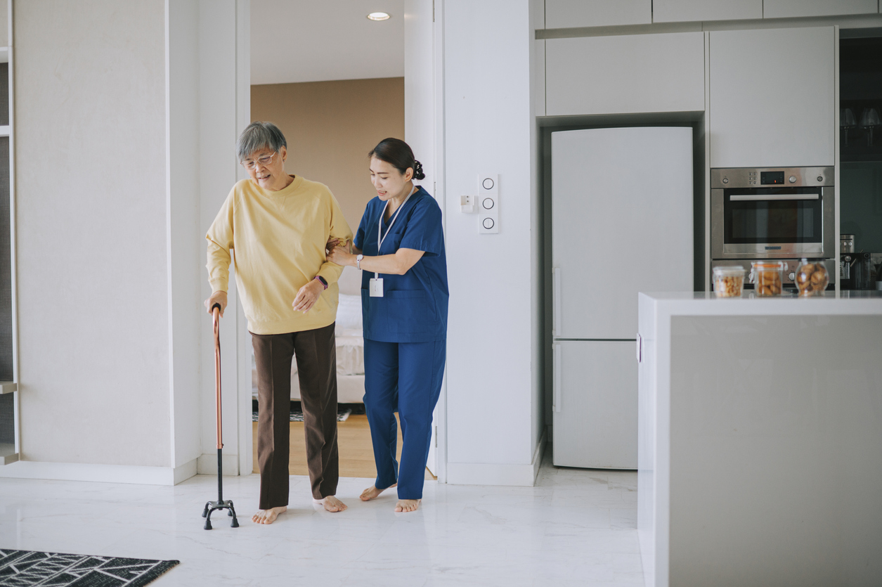 Man in assisted living walking with help from nurse